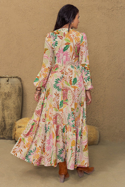 Long sleeve maxi dress with vibrant floral abstract print in green, orange, pink, and burgundy on a cream background, featuring buttons from mid-chest to mid-skirt and lace detailing around the neckline and under the bust.