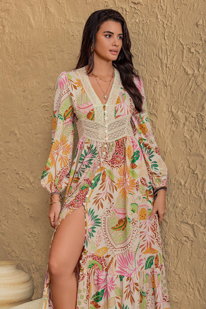 Long sleeve maxi dress with vibrant floral abstract print in green, orange, pink, and burgundy on a cream background, featuring buttons from mid-chest to mid-skirt and lace detailing around the neckline and under the bust.